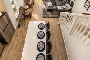 A modern kitchen with a central island, dining chairs, and a white railing.