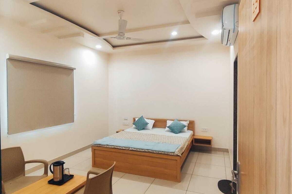 A bedroom with a wooden bed, a desk with a chair, a coffee maker, and a nightstand.