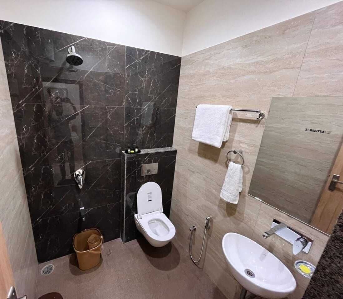 A modern bathroom with a marble vanity, a toilet, a sink, and a shower.