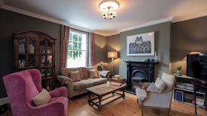 A cozy living room with a pink armchair, a wooden coffee table, a sofa, and a fireplace. - Linden House/Slane/Near NewGrange (Slane)