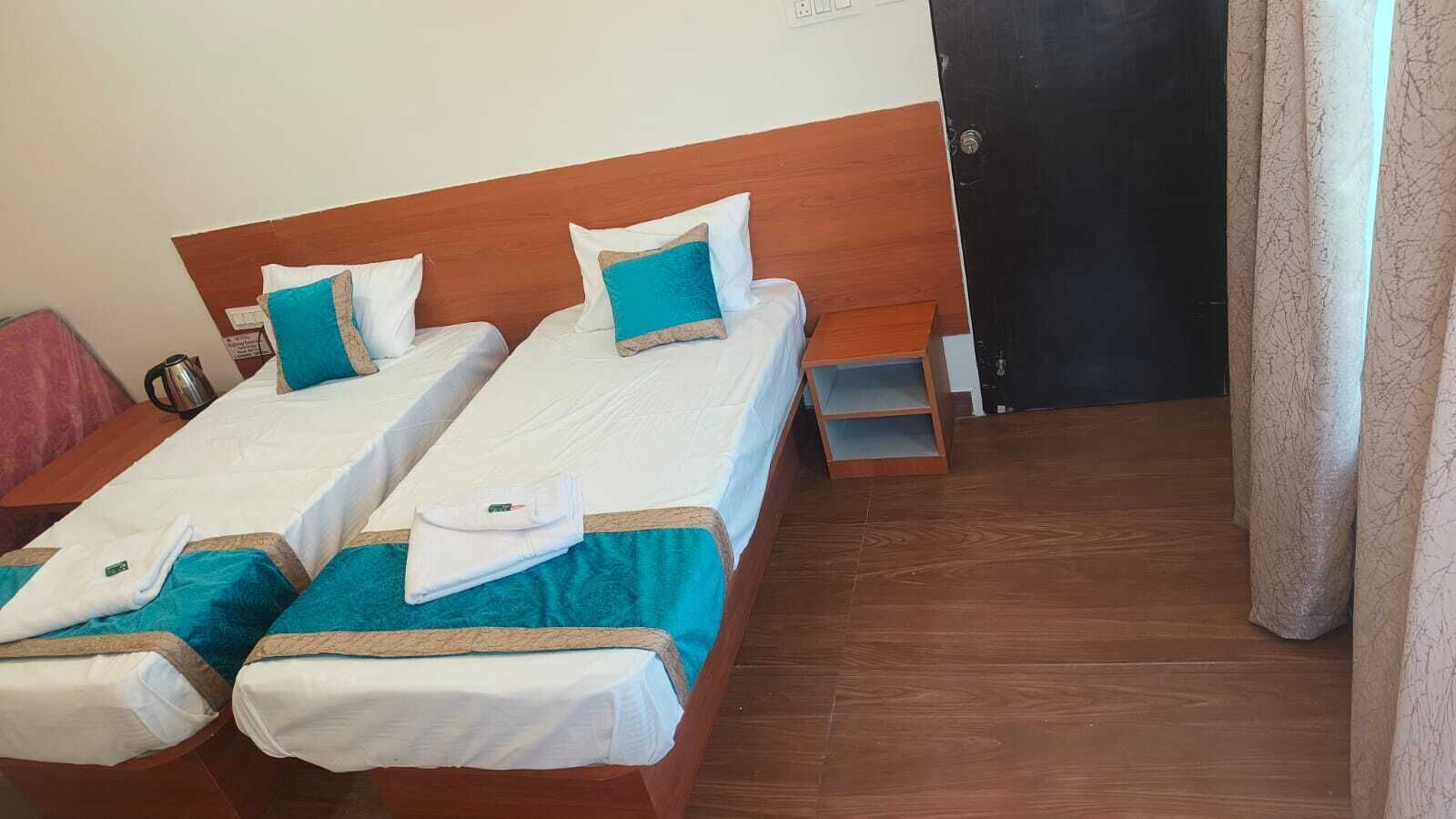 Een hotelkamer met twee eenpersoonsbedden, houten hoofdborden en een klein houten plankje.