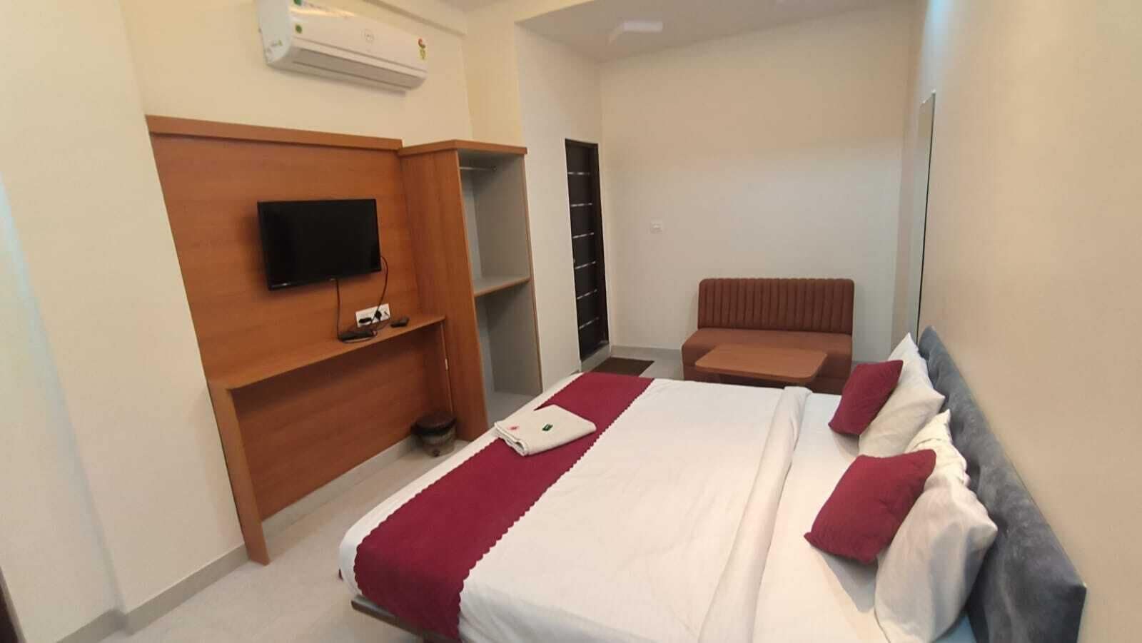 Habitación de hotel con cama, televisión, zona de estar y armario.