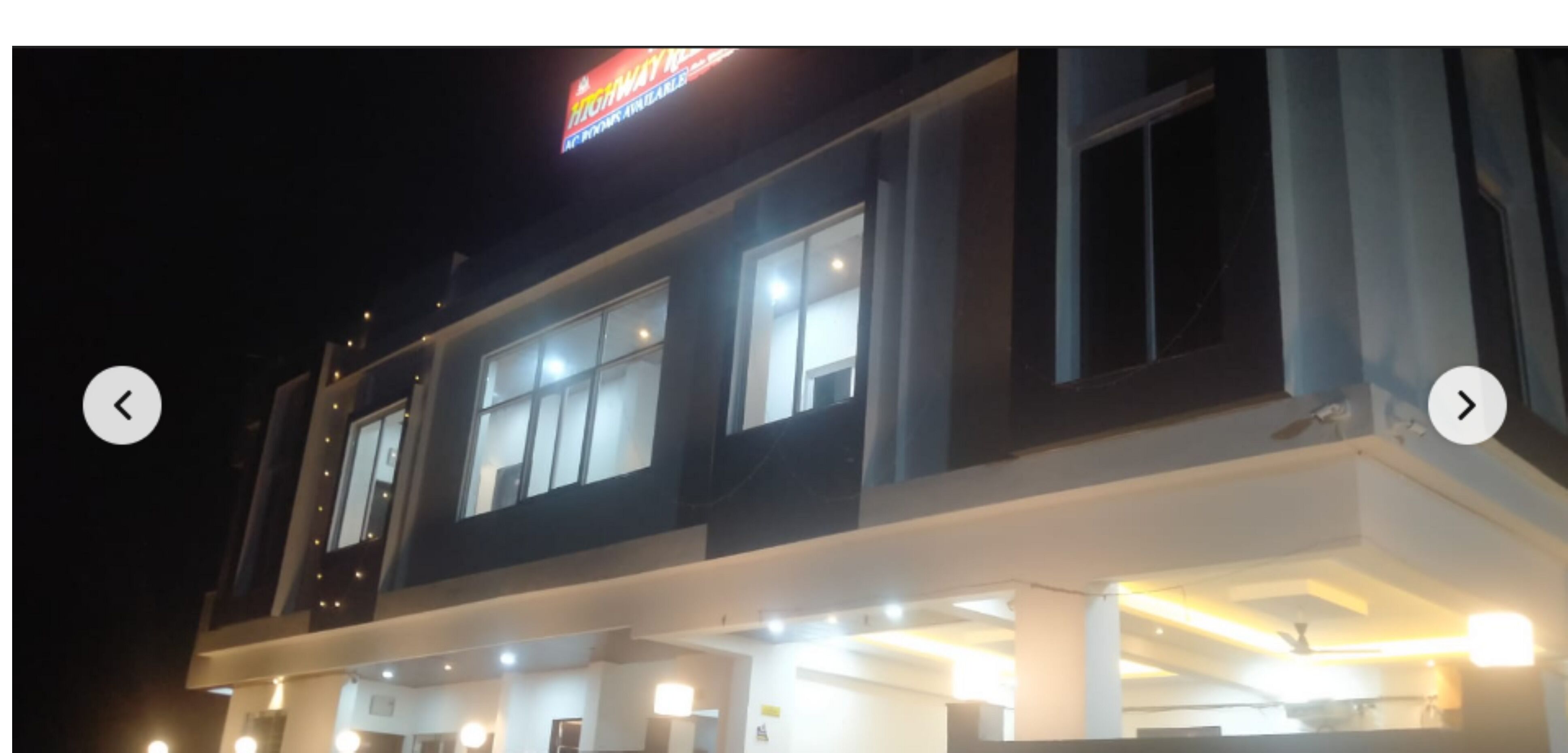 Un edificio de varios pisos con ventanas iluminadas y un letrero destacado en la parte superior.