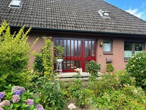Ein Haus mit roter Tür, Ziegelverkleidung und einem Ziegeldach.