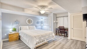 A bedroom with a bed, a desk, a chair, a ceiling fan, and a door. - 3203 Yacht Club Villas (North Myrtle Beach)