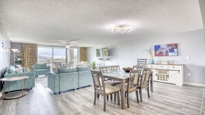 A spacious living area with a dining table, sofas, and a kitchen area. - 3203 Yacht Club Villas (North Myrtle Beach)