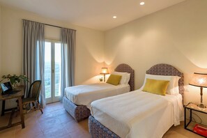 Une chambre d’hôtel avec deux lits, un bureau avec un ordinateur portable, une chaise et une vue par la fenêtre.