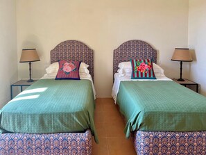 A double room with two beds, each with a patterned headboard and a green bedspread. There are two bedside tables with lamps. - Maniero in Maremma, luxury villa  in Tuscany (Montiano)