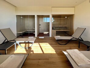 Une pièce équipée de deux tables de massage, d’un plancher en bois et d’une porte coulissante donnant accès à un espace douche.