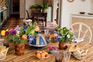 A dining table set with various dishes, including bread, fruits, and a blue and silver decorative item. - Maniero in Maremma, luxury villa  in Tuscany (Montiano)