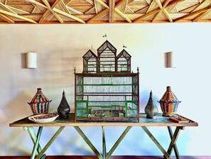 A model house with a green roof and multiple windows, displayed on a table with two decorative vases and a small bowl. - Maniero in Maremma, luxury villa  in Tuscany (Montiano)
