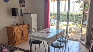 Un espace de vie compact comprenant une table à manger, des chaises, un meuble en bois, un téléviseur et un réfrigérateur.