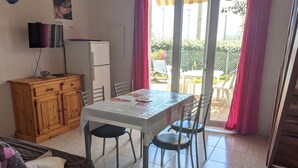 Une petite cuisine équipée d’un réfrigérateur, d’un meuble en bois et d’une table à manger avec des chaises.