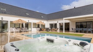 A modern outdoor pool area with lounge chairs, a hot tub, and a covered patio. - Luxurious Villa: Pool, Spa, Gym, Cinema, Near Beach, Sleeps 14 (La Turballe)