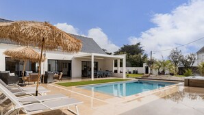 A modern house with a swimming pool, outdoor seating, and a covered patio area. - Luxurious Villa: Pool, Spa, Gym, Cinema, Near Beach, Sleeps 14 (La Turballe)