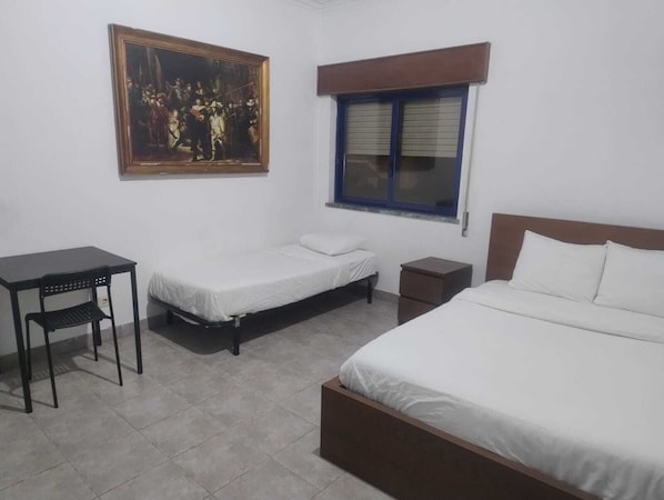 A room with two single beds, a desk, a chair, a small cabinet, and a painting on the wall. - Knowesgate Hotel (Newcastle-upon-Tyne)