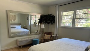 A bedroom with a large bed, a mirror, a small round table, a bench, and a potted plant. - Walkable neighborhood! The Sun House - Entire home to yourself (Atlanta)