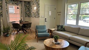 A living room with a dining area, a sofa, a coffee table, and a window with a view of the outside. - Walkable neighborhood! The Sun House - Entire home to yourself (Atlanta)