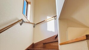 Un escalier en bois, doté d’une rampe et d’une petite fenêtre en haut.