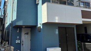 Un bâtiment à deux étages, avec une façade bleue, un étage supérieur blanc et une porte de garage.