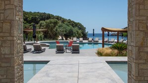 A pool area with lounge chairs and a view of the sea. - Arete Lifestyle Hotel (Igoumenitsa)