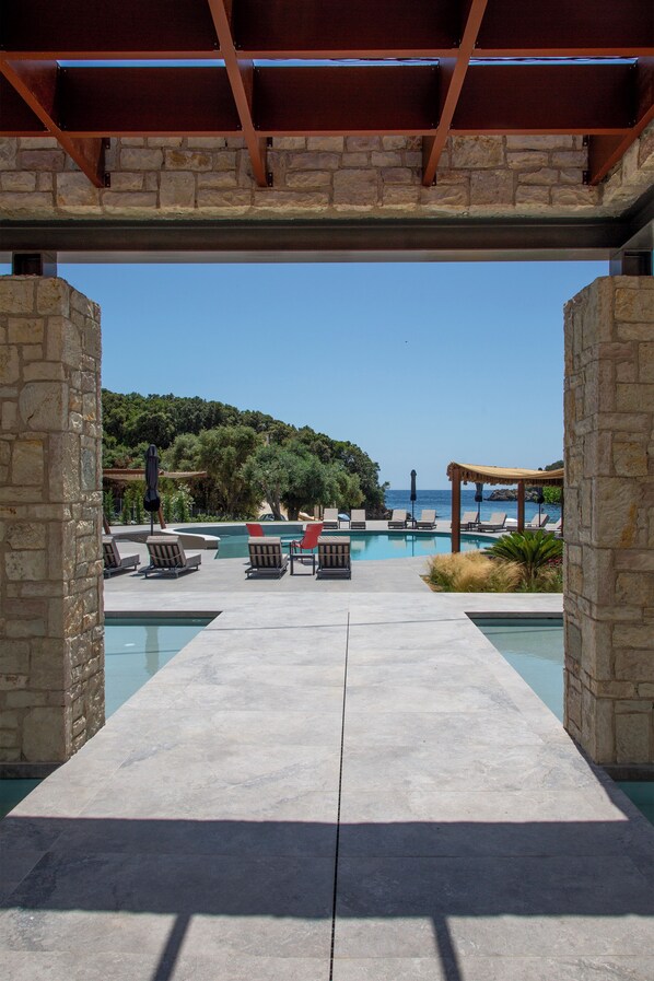 Zona de piscina con sillones de descanso y vista al mar.