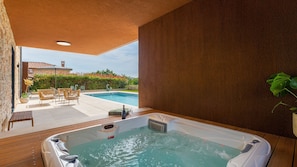 Un jacuzzi con vista a una piscina y zona de estar al aire libre.