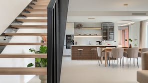 A modern kitchen with a central island, bar stools, and a dining area with chairs.