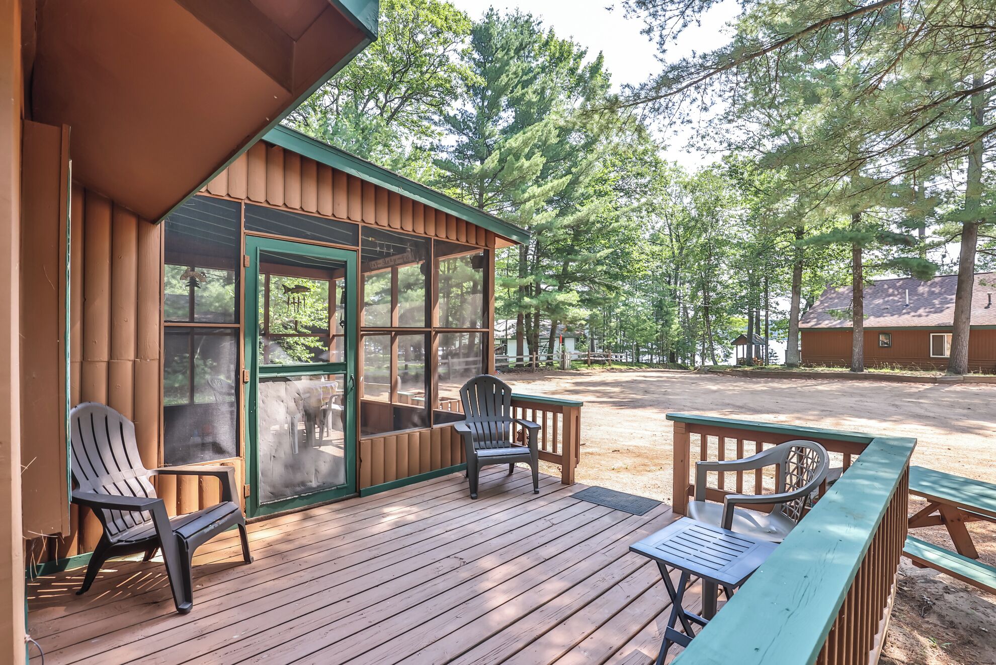 A wooden cabin with a deck, two chairs, and a table.