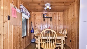 A wooden-paneled room with a table and chairs, a window, a broom, and a ceiling fan. - Estrold's Resort- Driftwood Cabin (St.Germain)