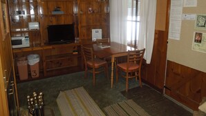 Une cuisine compacte dotée de meubles en bois, d’un four à micro-ondes, d’une télévision et d’une table à manger avec des chaises.