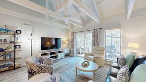 A modern living room with a flat-screen TV, a sofa, a coffee table, and a chair.