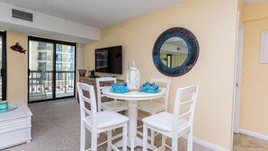 A dining area with a round table, white chairs, and a decorative mirror on the wall. - Oceanfront Building With Great Ocean and Bay Views (OCEAN OCEAN CITY)
