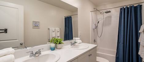 A modern bathroom with two sinks, a shower, and a toilet.
