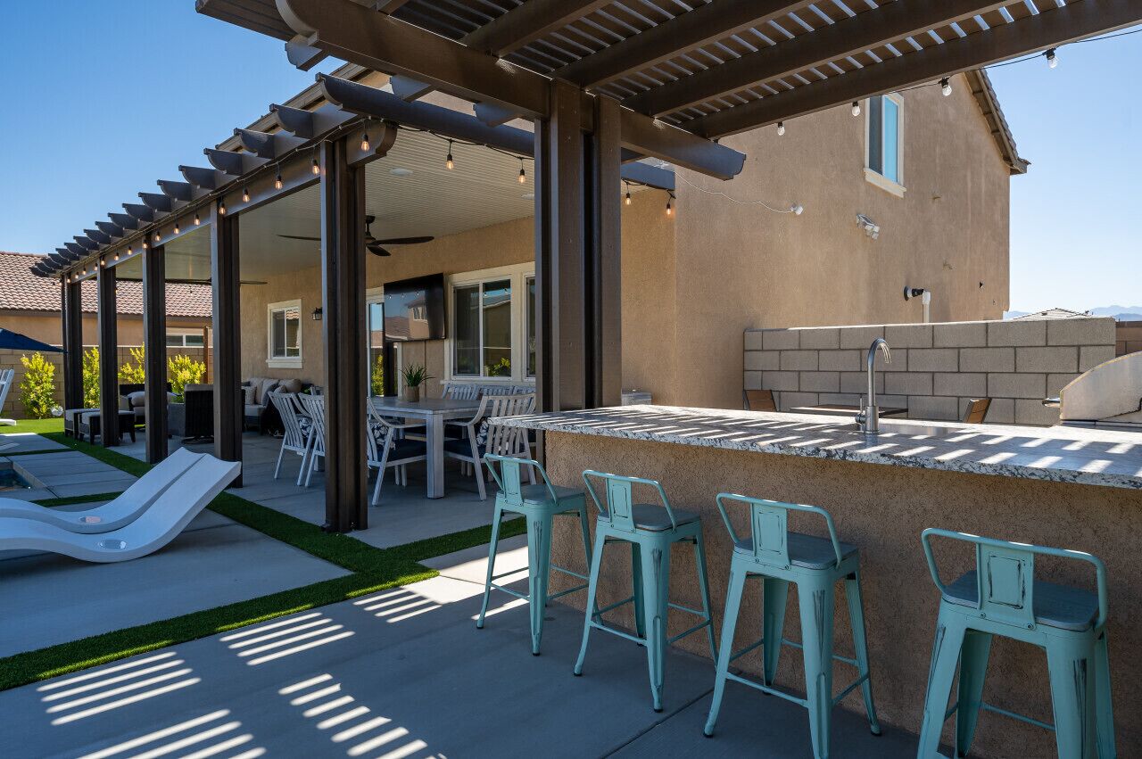 Une terrasse extérieure dotée d’une pergola, d’un espace barbecue et de sièges.