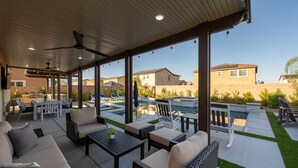 A covered patio area with outdoor furniture, a pool, and a view of neighboring houses. - Entertainer`s Paradise | Luxe Pool + Game Room (Coachella)