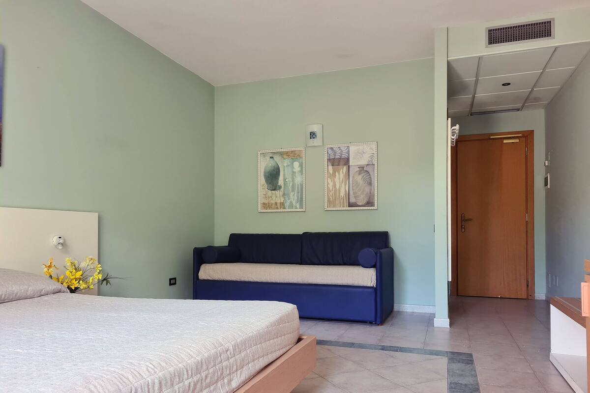 A bedroom with a bed, a sofa, and two wall art pieces.