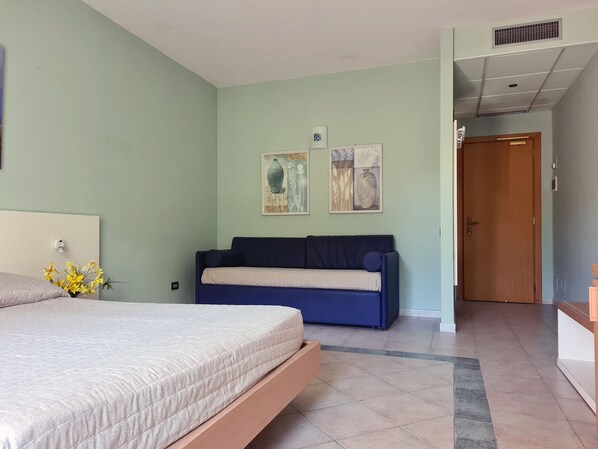 A bedroom with a bed, a sofa, and two wall art pieces. - Hotel La Buca Del Gatto (Cecina)