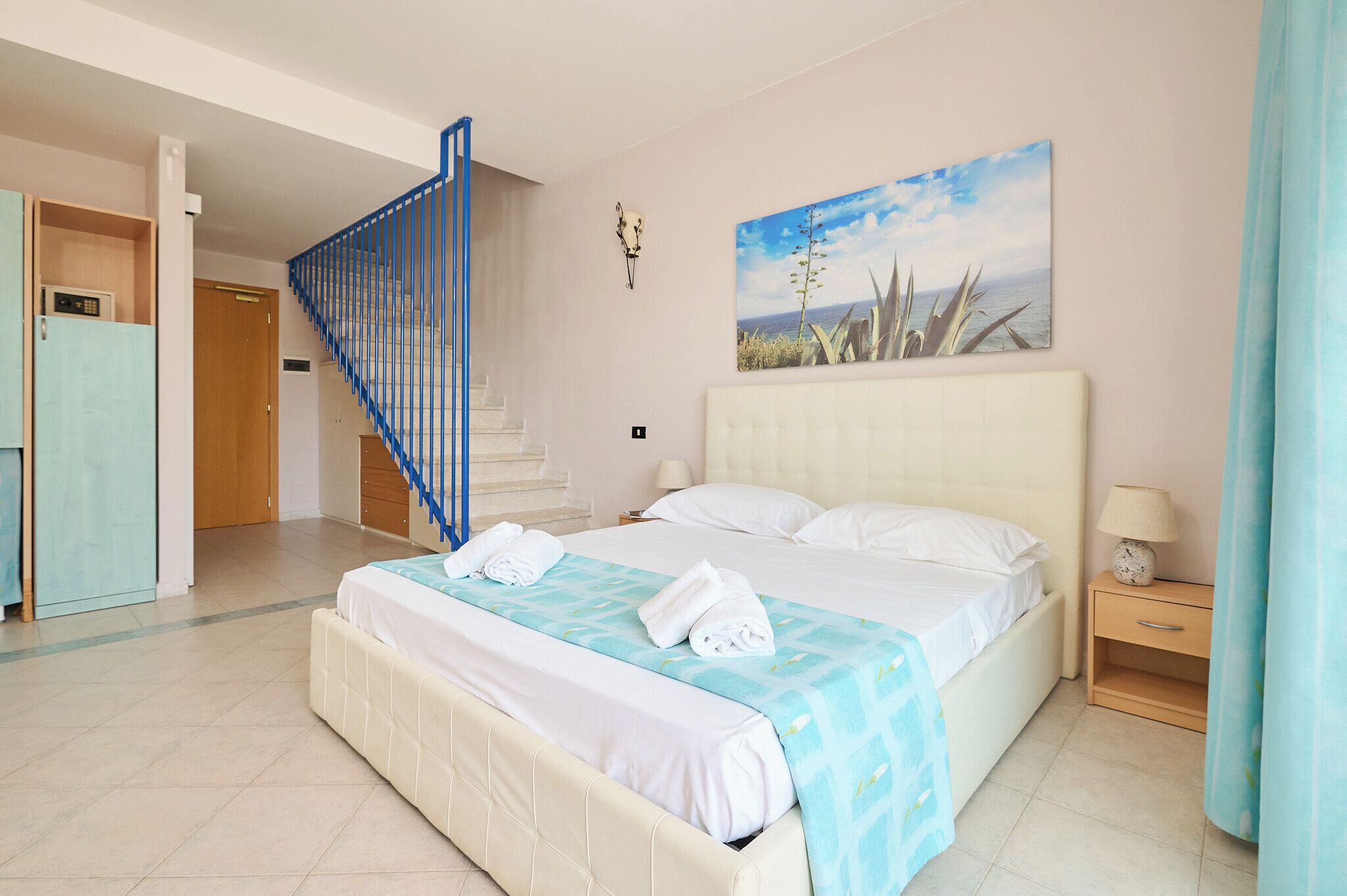 Una camera da letto con un letto, un comodino, una lampada, un quadro e una scala.