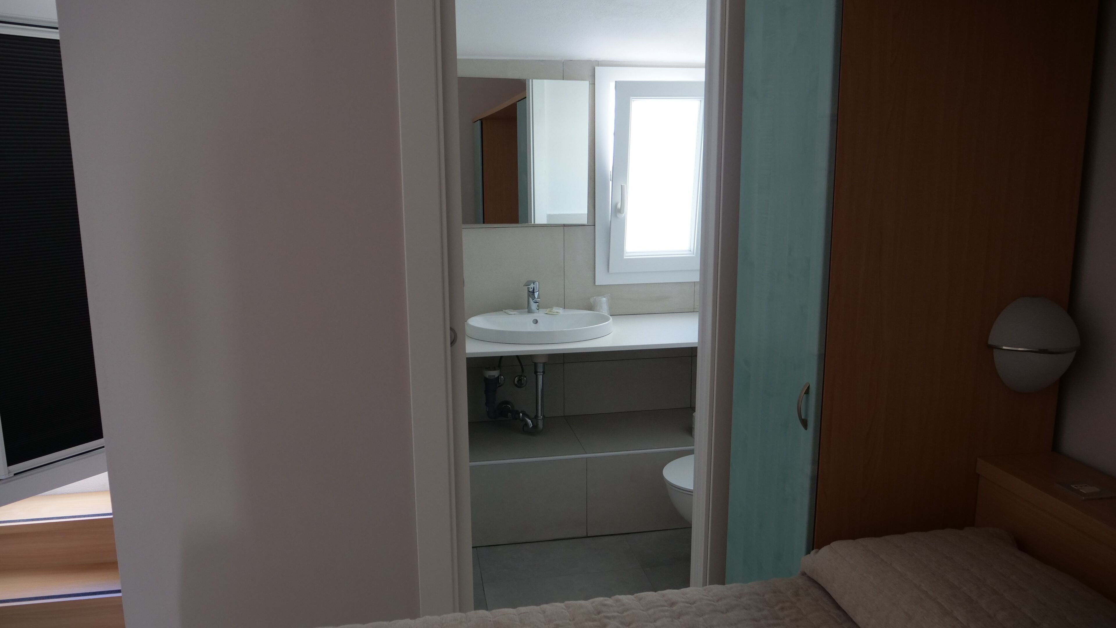 Un dormitorio con una cama, una mesita de noche y un ventanal.