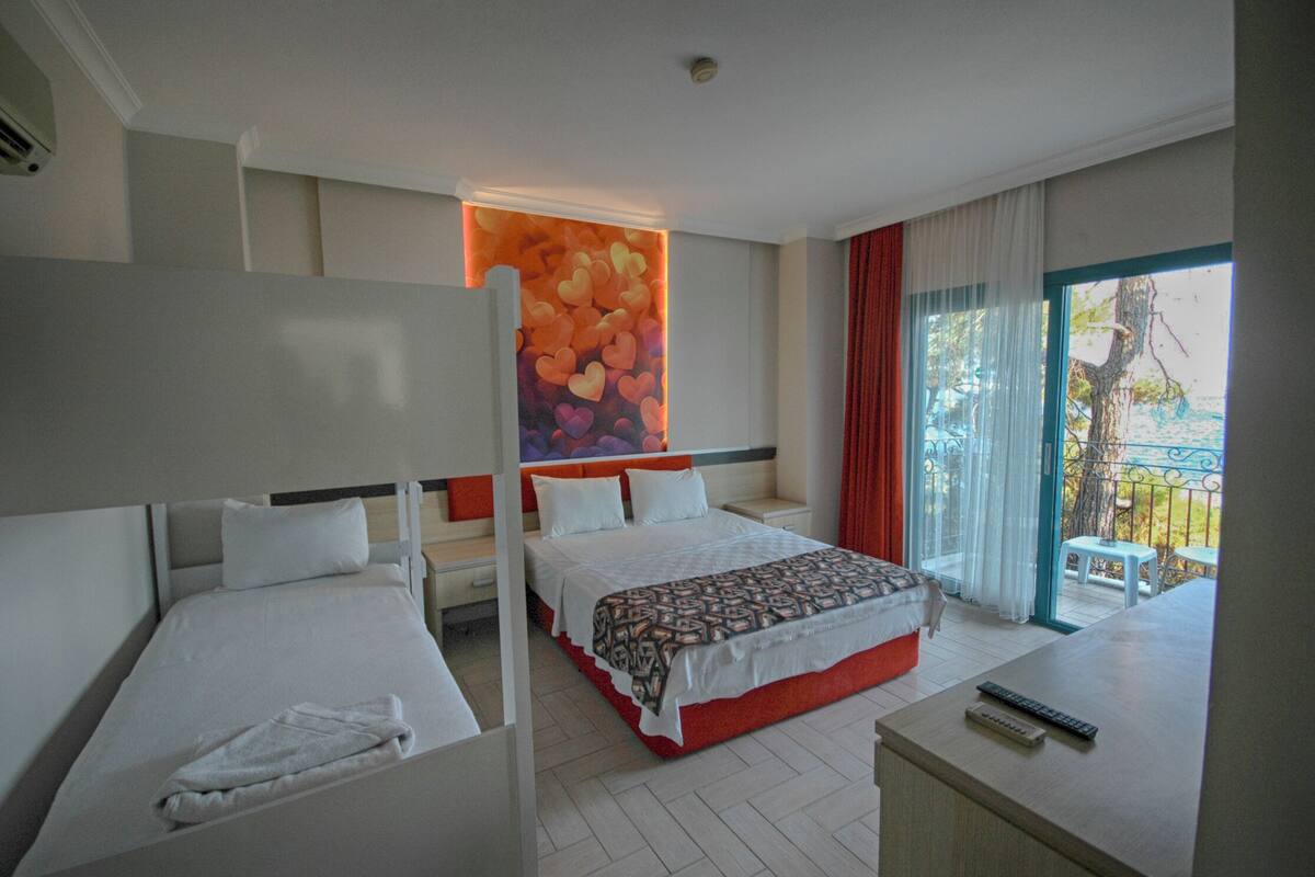 A hotel room with two beds, a large window with a view, and a balcony.