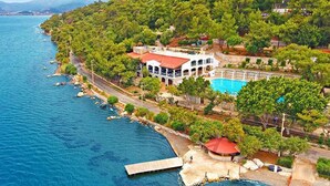 An aerial view of a coastal property with a swimming pool, a dock, and lush greenery. - Club Bellamare Beach (Marmaris)