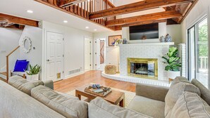 A spacious living room with a fireplace, wooden beams, and a staircase. - Waterfront Gainesville Home w/ Private Boat Dock! (Gainesville)