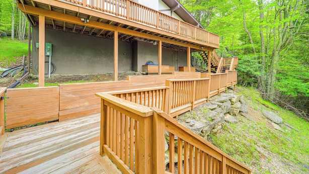 A wooden deck with a staircase leading to a covered area, surrounded by trees.