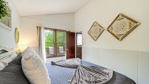 A bedroom with a large bed, a window with curtains, and two wall-mounted decorative plates.