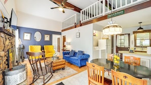 A dining area with a wooden table and chairs, a blue sofa, and a chandelier.