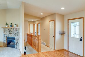 A spacious living room with a stone fireplace, wooden staircase, and a door with a decorative glass panel. - Roomy Piedmont Home w/ Yard < 14 Mi to Sturgis! (Piedmont)