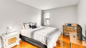 Une chambre à coucher avec un lit, une table de chevet, une commode et une fenêtre.