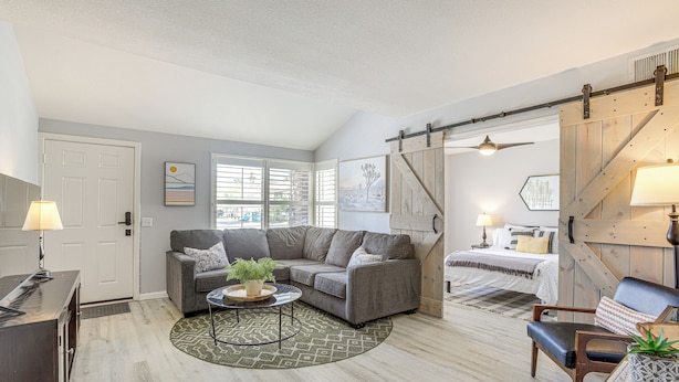 A modern living room with a gray sectional sofa, a coffee table, and a wooden floor. - Pool Access & Mtn Views: Palm Springs Retreat! (Palm Springs)