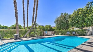 A clear blue swimming pool with a tiled edge, surrounded by palm trees and a hedge. - Pool Access & Mtn Views: Palm Springs Retreat! (Palm Springs)